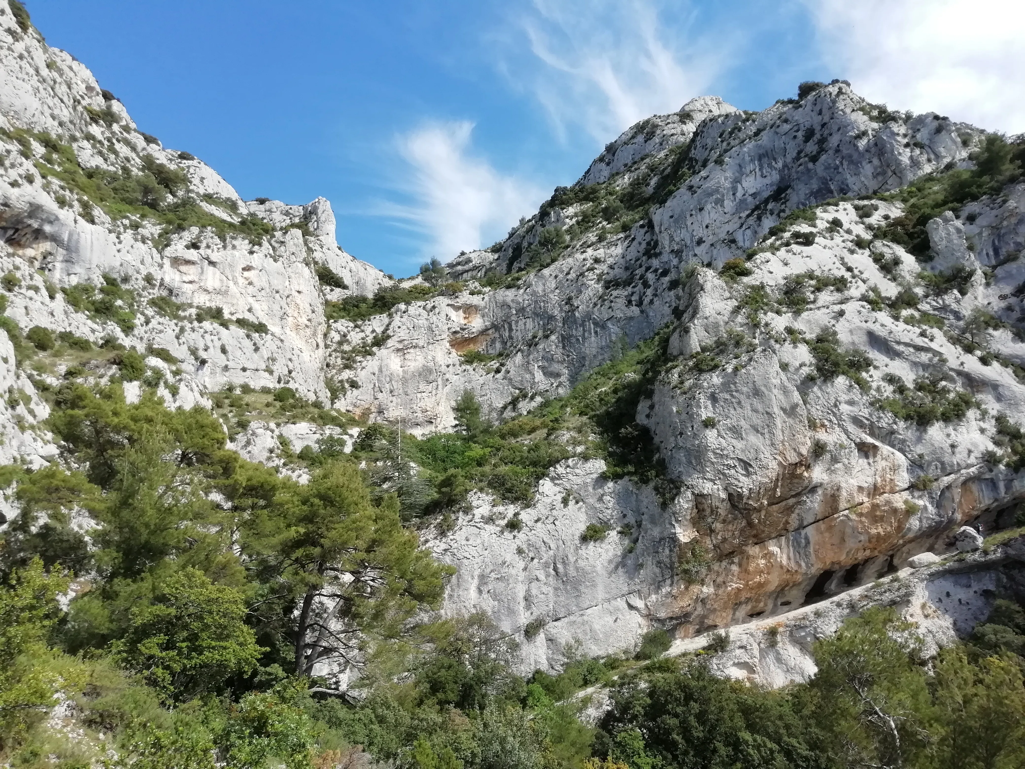 Un cirque de falaises calcaires piquées de pins, avec une route taillée dans la paroi