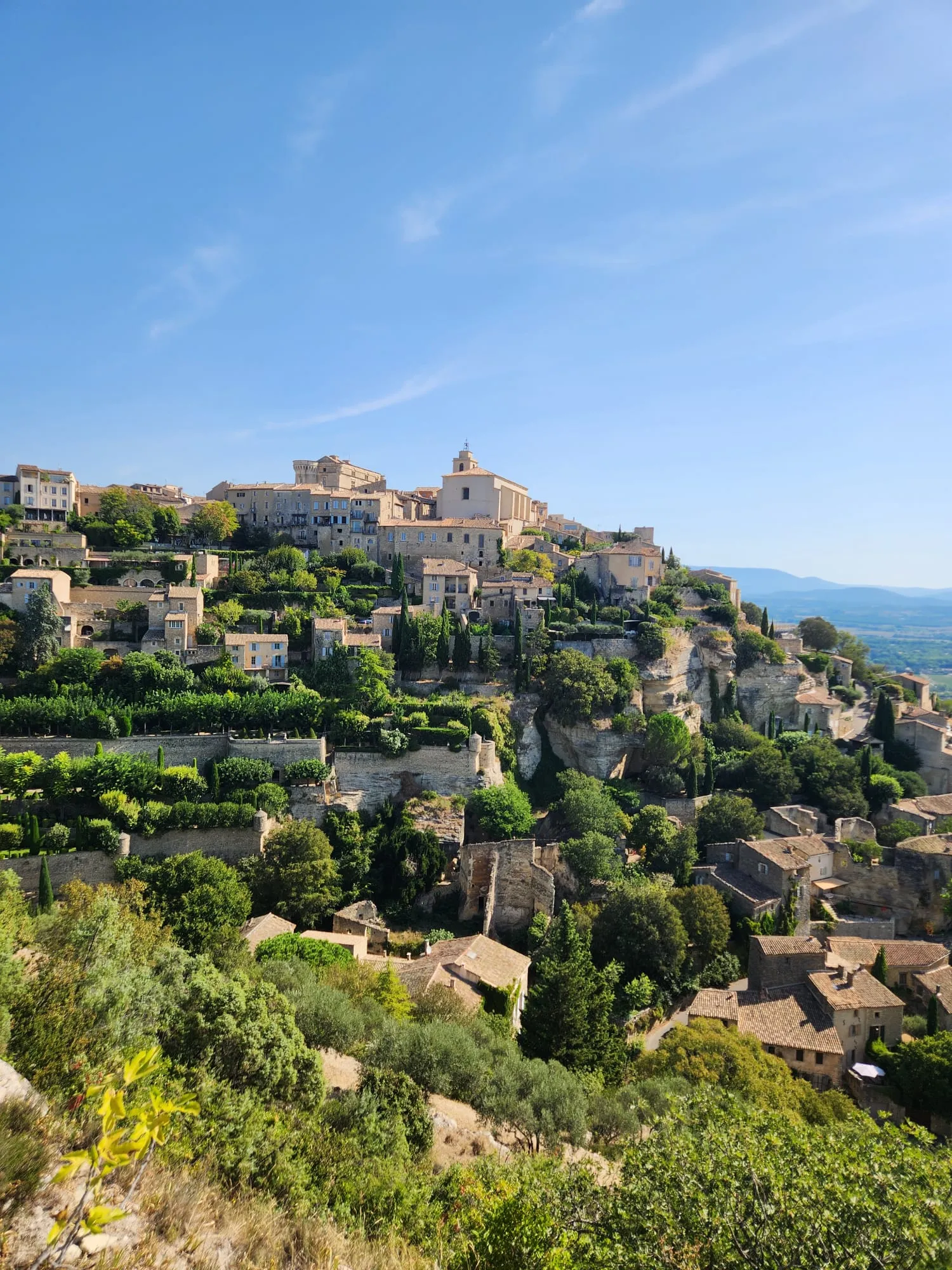 Un village de pierre bâti sur un éperon rocheux, ses jardins en terrasses et ses cyprès, la plaine au loin